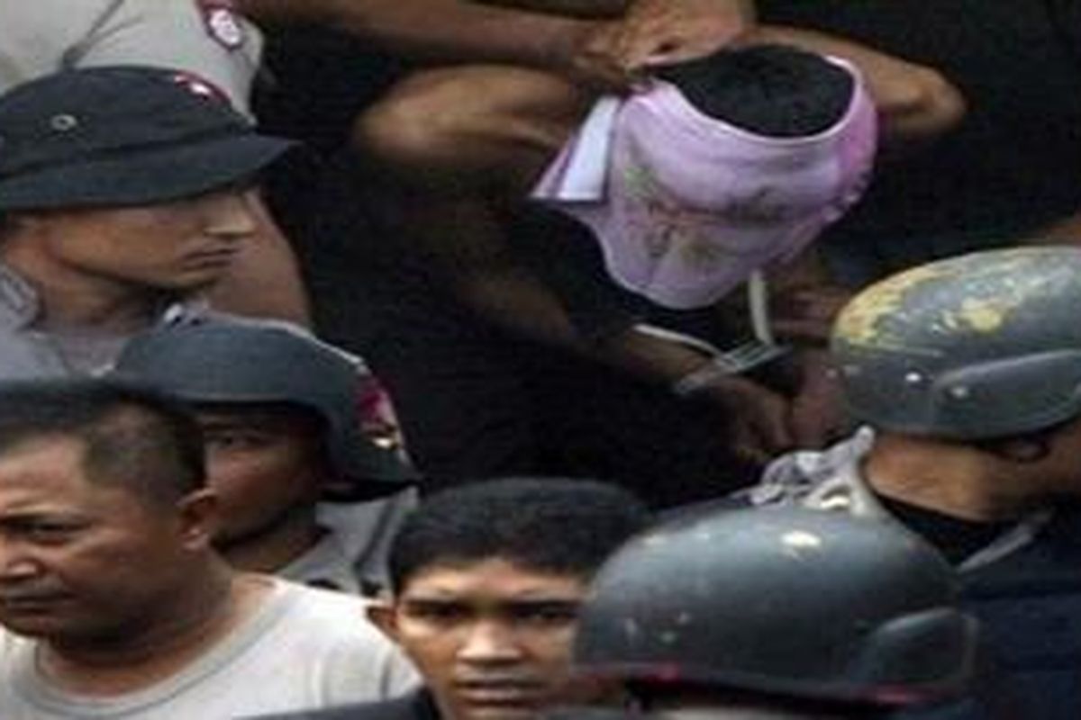 Police officers escort a suspected militant arrested after a gunfight in Leupung, Aceh province, Indonesia, Friday, March 12, 2010. Indonesian police killed two suspected Islamist militants in a firefight in remote Aceh province Friday during the latest in a series of raids made since an extremist training camp was discovered there last month. Eight other suspects were arrested.