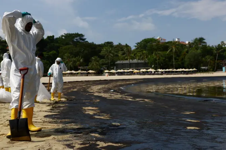 Para Pekerja yang menggunakan baju pelindung membersihkan tumpahan minyak di obyek wisata Pantai Tanjong, Minggu.