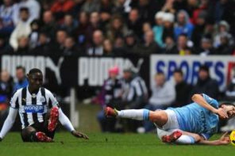 Gelandang Manchester City, Samir Nasri, terjatuh setelah ditekel bek Newcastle United, Mapou Yanga-Mbiwa, saat kedua tim berlaga di Premier League, Minggu (12/1/2014).