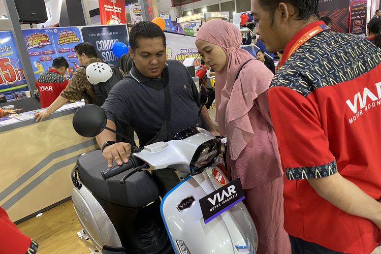 Pengunjung Jakarta Fair 2023 melihat-lihat produk motor listrik baru