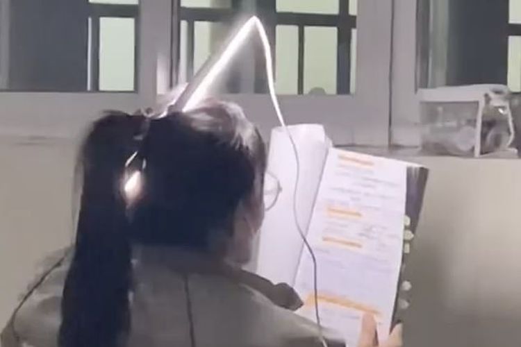 Seorang mahasiswi China menjadi ikon kerja keras nasional yang baru setelah tertangkap kamera mengikatkan lampu neon di rambutnya sehingga dia bisa belajar dalam gelap.