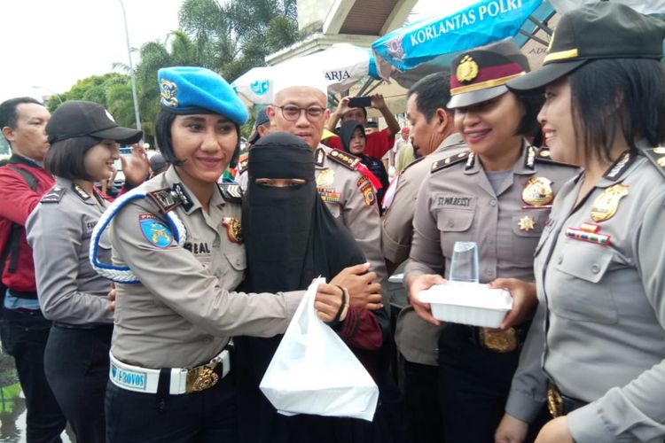 Seorang Anggota Polwan yang bertugas di Provost Polda Maluku memeluk erat seorang wanita bercadar di acara pembagian makanan berbuka yang digelar Polda Maluku di Jalan AM Sangadji Ambon, Jumat petang (25/5/2018).