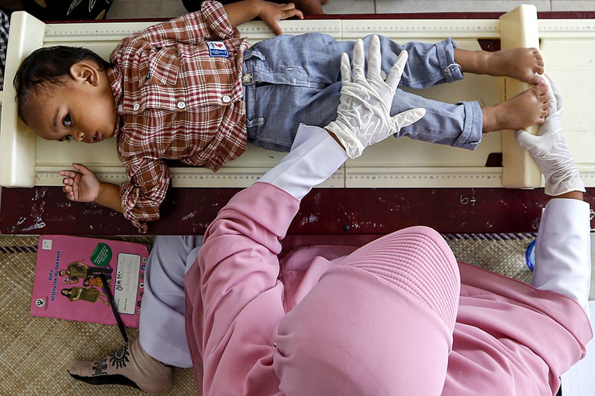 Petugas puskesmas Ulee Kareng mengukur tinggi badan balita sebelum memberikan imunisasi di Desa Ilie, Banda Aceh, Aceh, Selasa (16/6/2020). Penurunan jumlah imunisasi terhadap balita selama pandemi mendorong tenaga medis puskesmas di Banda Aceh untuk meningkatkan kembali imunisasi dengan sistem jemput bola.