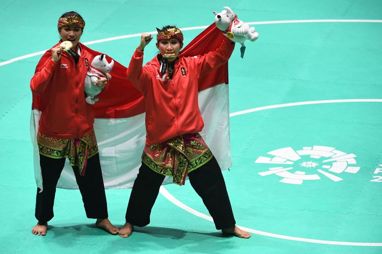 Pasangan pesilat Indonesia peraih medali emas Ayu Sidan Wilantari (kiri) dan Ni Made Dwiyanti (kanan) berpose usai upacara penyerahan medali nomor ganda putri pencak silat seni Asian Games 2018 di Padepokan Pencak Silat Taman Mini Indonesia Indah (TMII), Jakarta, Rabu (29/8/2018).