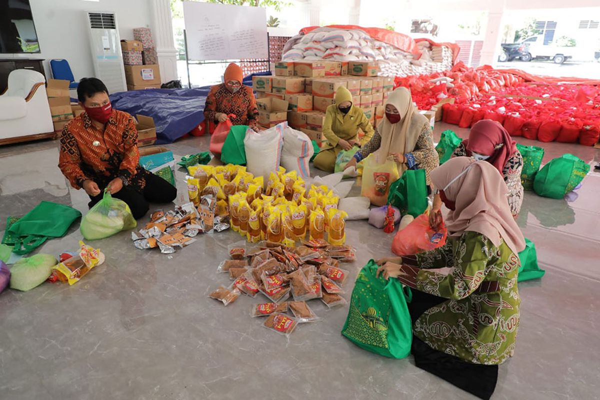 BANTU PENGEPAKAN - Wali Kota Madiun Maidi bersama istrinya yang juga sebagai Ketua TP PKK Kota Madiun, Yuni Setyawati Maidi membantu proses pengepakan sembako untuk segera didistrubusikan bagi warga yang terdampak Covid-19. 