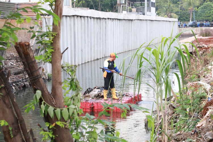 Petugas terlihat membersihkan sampah yang mengotori saluran air di Jakarta.