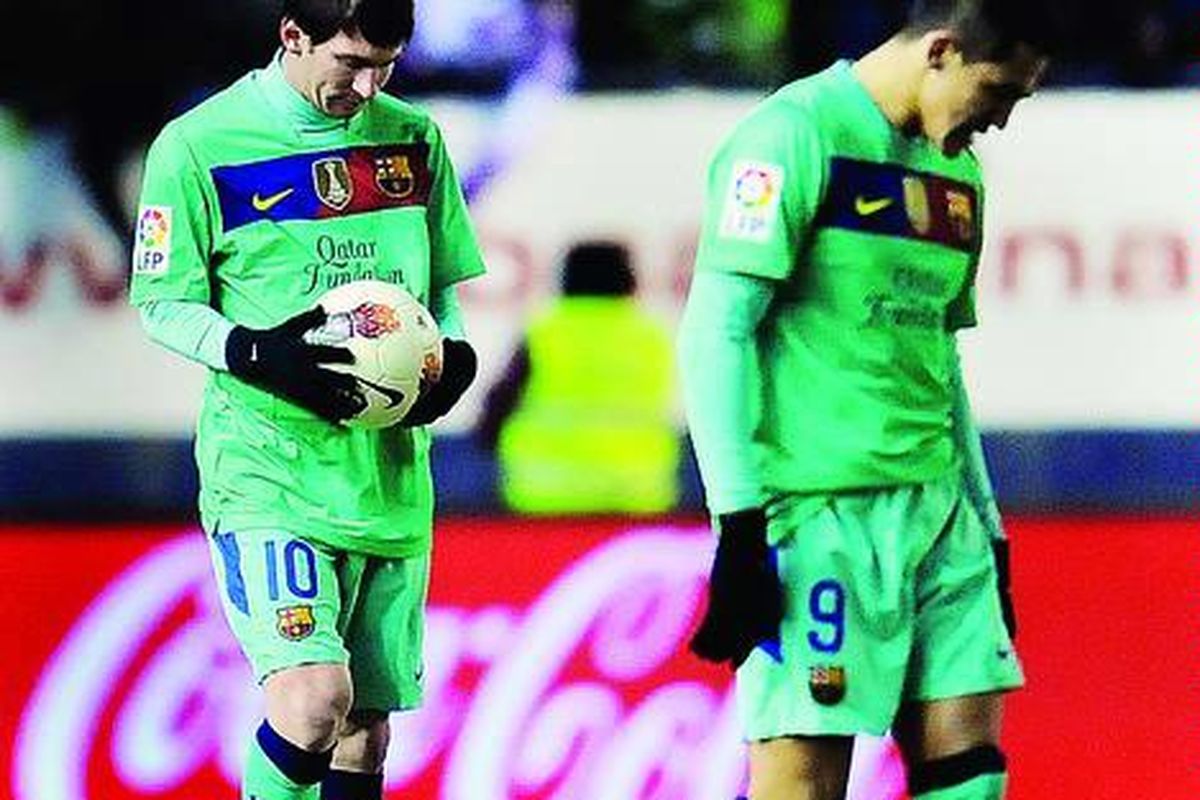 Pemain Barcelona, Lionel Messi (memegang bola), berjalan menunduk bersama rekannya, Alexis Alejandro, setelah dikalahkan tuan rumah Osasuna pada lanjutan Liga Spanyol di Stadion Reyno de Navarra di Pamplona, Sabtu (11/2). Barcelona kalah 2-3.