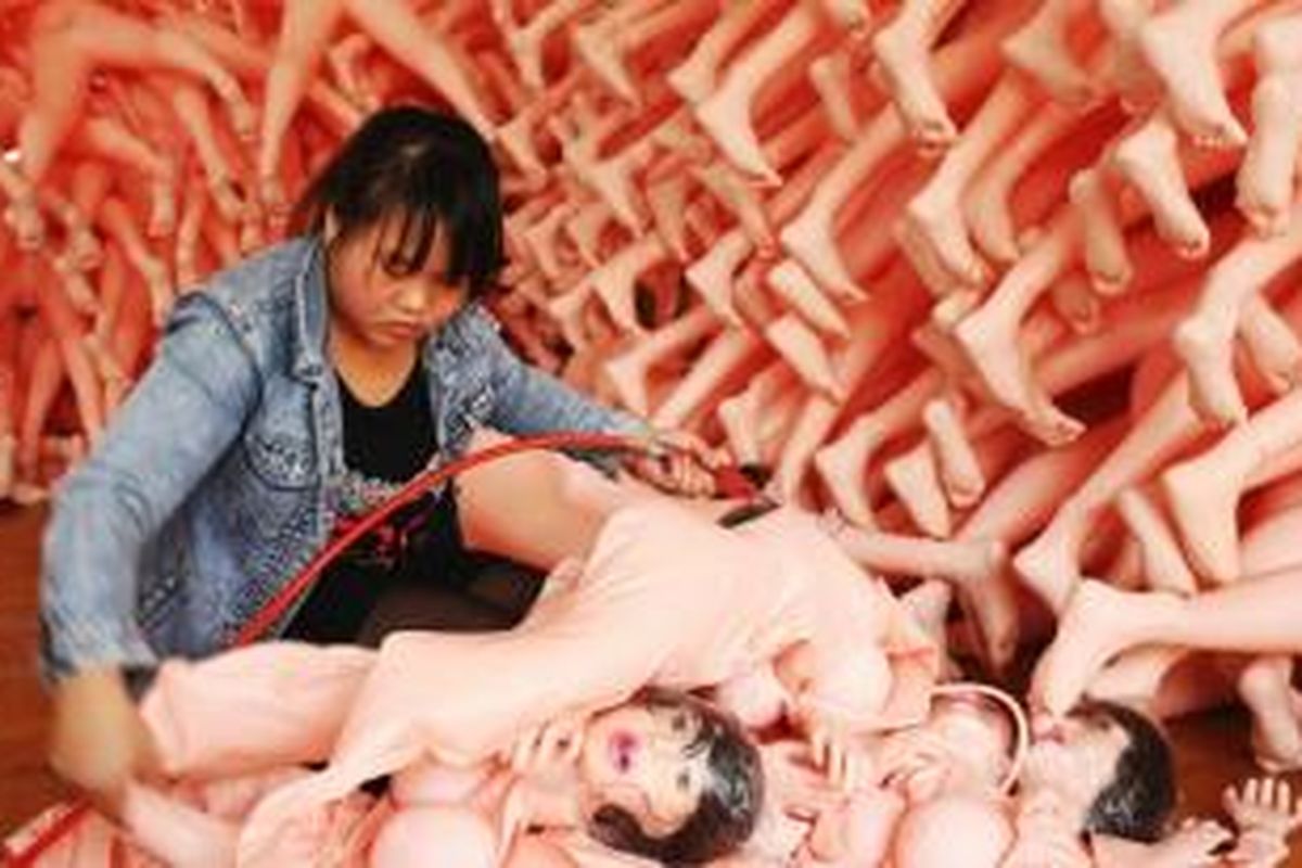 Seorang pekerja tengah memompa sebuah boneka seks dikelilingi ribuan boneka lainya di salah satu pabrik mainan seks di kota Ningbo, China.