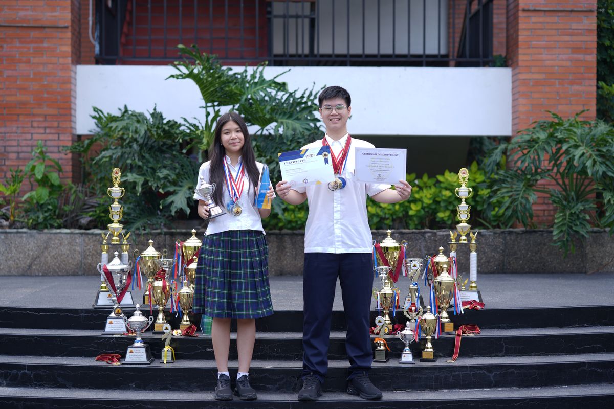 (ki-ka) Ava Mikayla Emmanoelle Kasih (14) dan Sean Levi Danuseputra (15) tengah berpose dengan memakai medali, dikelilingi piala, dan memegang sertifikat kompetisi mereka.