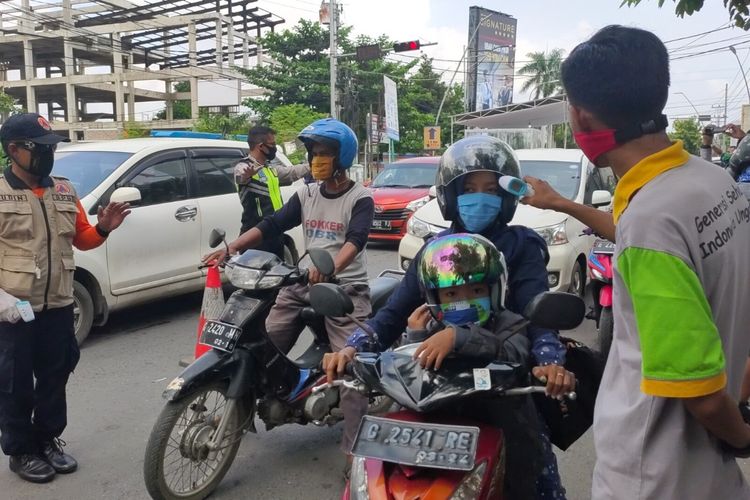 Petugas memeriksa suhu tubuh pengendara yang melintas di Pos Chek Point di Jalan Sultan Agung Kota Tegal, saat penerapan isolasi wilayah menjelang PSBB, Selasa (21/4/2020)