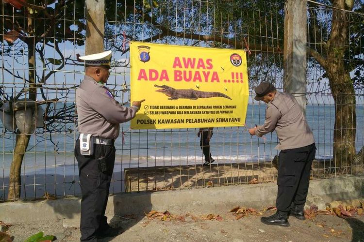 Polisi memasang spanduk peringatan pasca kemunculan buaya di Pantai Semayang, Balikpapan