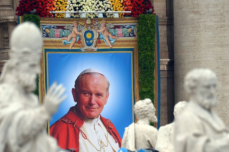 The tapestry showing Pope John Paul II is pictured amid statues during the canonisation mass of Popes John XXIII and John Paul II on St Peter's at the Vatican on April 27, 2014. Catholics from around the world gathered in Rome on Sunday for a mass presided by Pope Francis to confer sainthood on John Paul II and John XXIII -- two influential popes who helped shape 20th century history.       AFP PHOTO / VINCENZO PINTO (Photo by VINCENZO PINTO / AFP)
