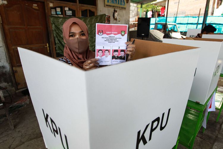 Warga menggunakan hak pilihnya di Tempat Pemungutan Suara (TPS) 39 Banjarsari, dalam pemilihan Walikota dan Wakil Walikota Solo, Rabu (9/12/2020). Mengangkat tema TPS sadar protokol kesehatan, petugas TPS 39 terlihat mengenakan hasmat serta warga yang datang diwajibkan menggunakan masker, mencuci tangan, dan mengenakan sarung tangan.