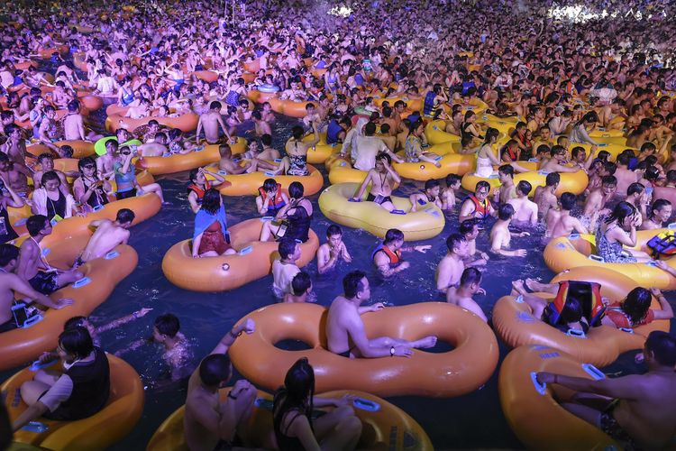 Foto tertanggal 15 Agustus 2020 menunjukkan orang-orang menonton pertunjukan musik sambil bermain air di Wuhan, Provinsi Hubei, China.
