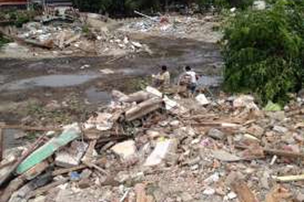 Tampak dua warga yang habis memunguti sisa reruntuhan bangunan di Kalijodo berjalan menuju ke seberang, Senin (29/2/2016). 



