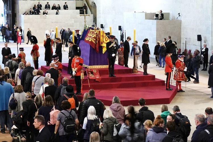 Cucu-cucu Ratu Elizabeth II berjaga-jaga di sekitar peti mati Ratu Elizabeth II, terbungkus Standar Kerajaan dengan Mahkota Negara Kekaisaran dan bola dan tongkat kerajaan, tergeletak di catafalque di Westminster Hall, di Istana Westminster di London pada 17 September 2022, menjelang pemakamannya pada Senin.