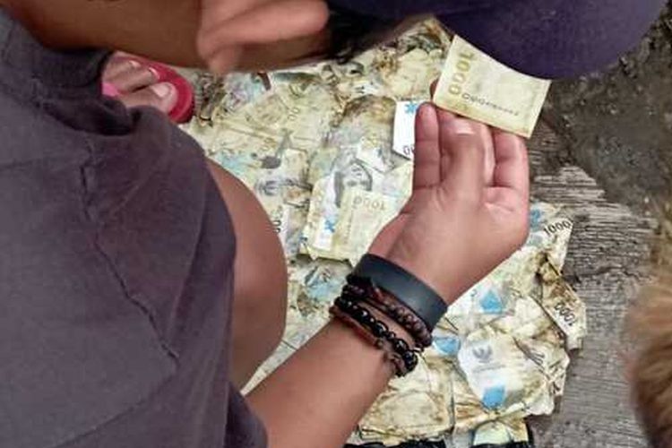 Warga berebut uang kertas pecahan Rp 1000 yang ditemukan di saluran air di wilayah Cimalaka, Sumedang, Jabar. 