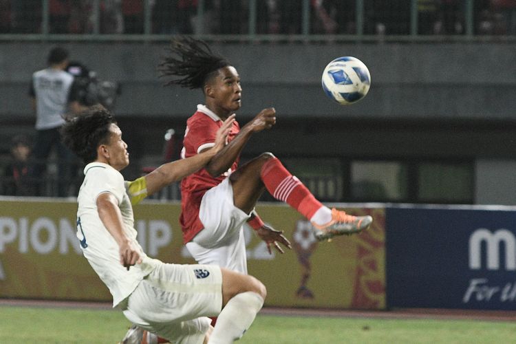 Pesepak bola Tim Nasional Indonesia U-19 Ronaldo Kwateh (kanan) dihadang pesepak bola Tim Nasional Thailand U-19 Chanapach Buaphan (kiri) dalam laga penyisihan Grup Piala AFF U19 2022 di Stadion Patriot Chandrabhaga, Bekasi, Jawa Barat, Rabu (6/7/2022). ANTARA FOTO/ Fakhri Hermansyah/foc.