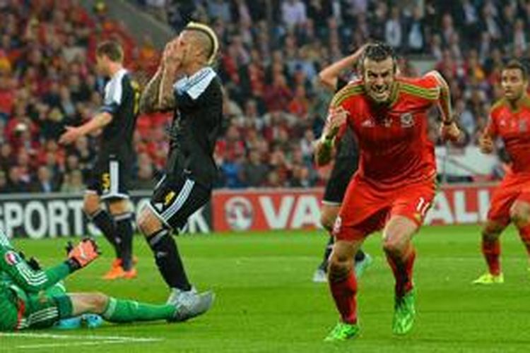 Gareth Bale mencetak gol ke gawang Thibaut Courtois saat Wales berhadapan dengan Belgia, Jumat (12/6/2015). 