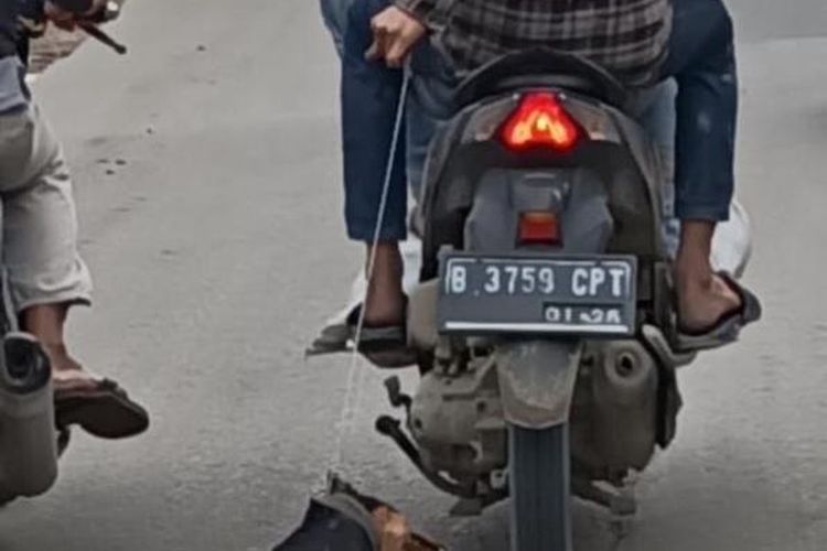 Dua pria bermotor yang menyeret seekor anjing ketika difoto oleh salah seorang pengendara motor di Dumpit, Jatiuwung, Kota Tangerang, Senin (1/2/2021). (istimewa)
