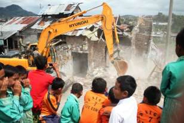 Sejumlah pelajar dari berbagai sekolah sedang menyaksikan pembongkaran satu unit rumah berkontruksi unik oleh Satpol PP Aceh Tengah dibantu satu unit alat berat yang dipesan oleh aparat desa di Kampung Asir-asir, Kecamatan Lut Tawar, Kabupaten Aceh Tengah, Aceh, Sabtu (8/10/2016).