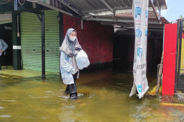 Salah satu warga melintasi genangan banjir di Kelurahan Bintoro, Kecamatan Demak, Kabupaten Demak, Selasa (19/3/2024). (KOMPAS.COM/NUR ZAIDI)