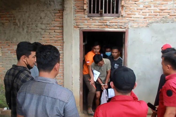 Tersangka E saat proses rekonstruksi kasus pembunuhan di Desa Marga Jaya, Way Kanan, Jumat (7/10/2022).