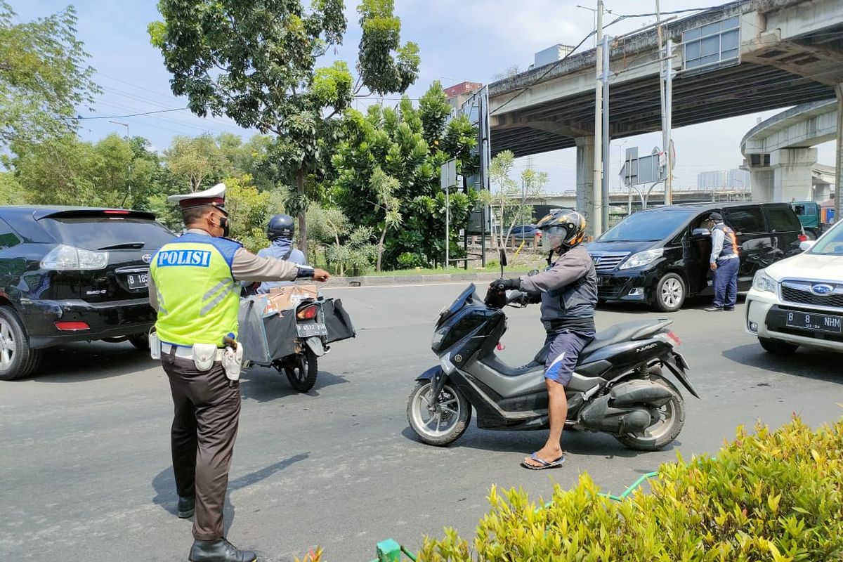 Seorang polantas mengarahkan pengendara motor berpelat genap agar putar balik karena aturan ganjil genap di jalan arah wisata Ancol, Jakarta Utara, Sabtu (23/10/2021). 