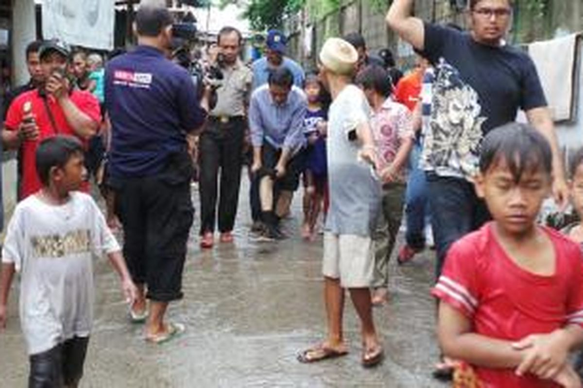Gubernur DKI Jakarta Joko Widodo (Jokowi) menggulung celananya yang basah setelah dia menerjang banjir ketika meninjau lokasi banjir dan rumah pompa di Pluit, Jakarta Utara, Minggu (19/1/2014)