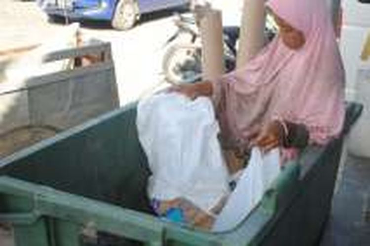 Dian Nurlianti (11) bocah SD kelas IV saat memungut sampah di salah satu toko