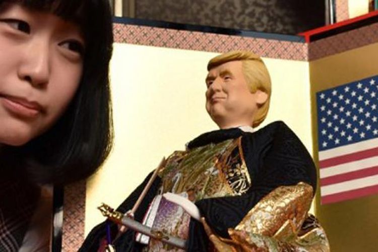 Seorang pegawai dari perusahaan pembuat boneka tradisional Jepang hina Kyugetsu, memegang produk terbaru mereka yang mirip dengan sosok Presiden AS Donald Trump. Patung ini dipajang di gerai perusahaan tersebut, di Tokyo, Jepang, Kamis (26/1/2017).  