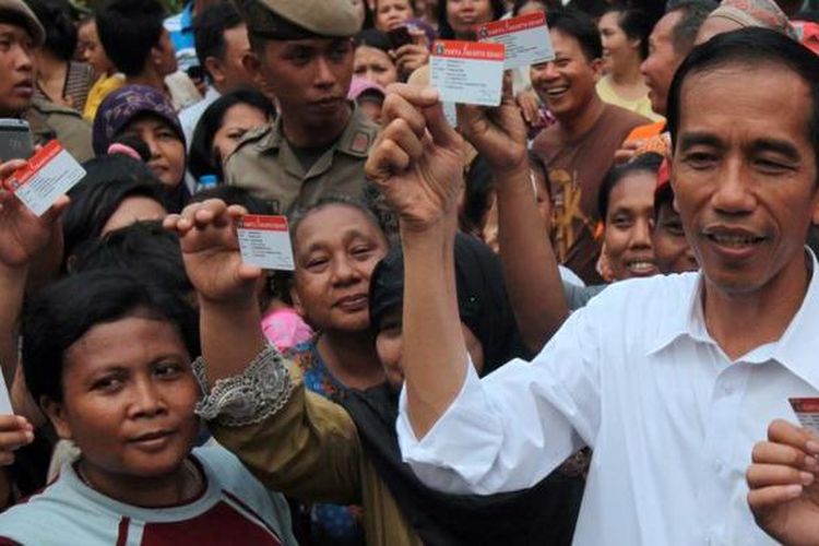 Bersama perwakilan warga penerima Kartu Jakarta Sehat,  Gubernur DKI Jakarta Joko Widodo menunjukkan kartu seusai perkenalan program itu di Kelurahan Pademangan Timur, Jakarta Utara, Sabtu (10/11/2012). Kartu jaminan pengobatan gratis bagi warga di Puskesmas atau Kelas 3 di 88 rumah sakit yang bekerja sama dengan pemerintah provinsi.

