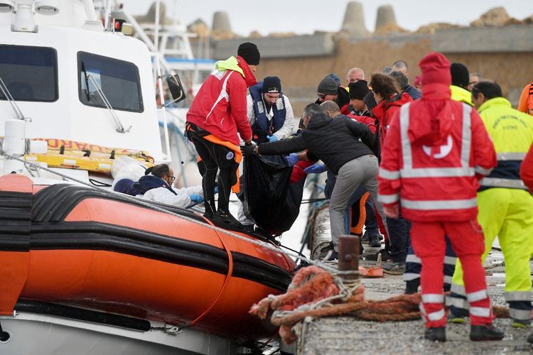 Petugas Penjaga Pantai Italia membawa jenazah migran yang meninggal di dalam tas, pada 27 Februari 2023 di pelabuhan Isola di Capo Rizzuto, selatan Crotone, setelah kapal migran tenggelam di wilayah Calabria selatan Italia. 