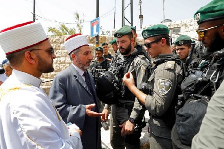 Umat Muslim Palestina berbicara dengan petugas Israel yang berjaga di depan Lions Gate, pintu masuk utama ke Masjid Al-Aqsa, di Kota Tua Yerusalem, Jumat (21/7/2017). Israel melarang pria Palestina yang berusia di bawah 50 tahun untuk masuk ke kawasan Kota Tua dan menjalani Shalat Jumat, menyusul insiden penembakan dua polisi Israel.