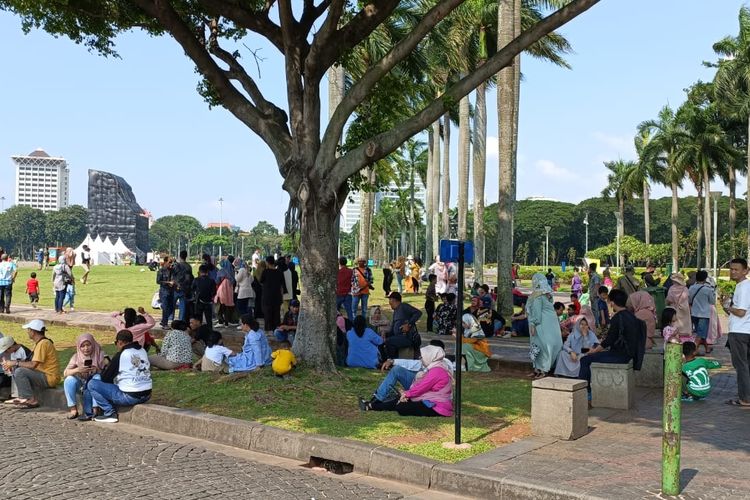 Pengunjung di area Monumen Nasional (Monas), Jakarta Pusat pada Senin (24/4/2023) siang. Sejumlah pengunjung terlihat berteduh di bawah pohon rindang karena cuaca panas terik yang terjadi.