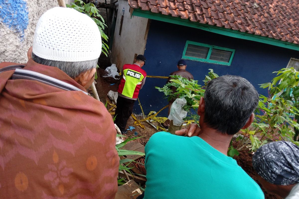 Sejumlah warga menonton seorang anggota polisi yang memasang garis pembatas di rumah tersangka Solihin di Cianjur, Jawa Barat. Di rumah ini ditemukan dua jenazah yang dikubur dalam satu lubang.