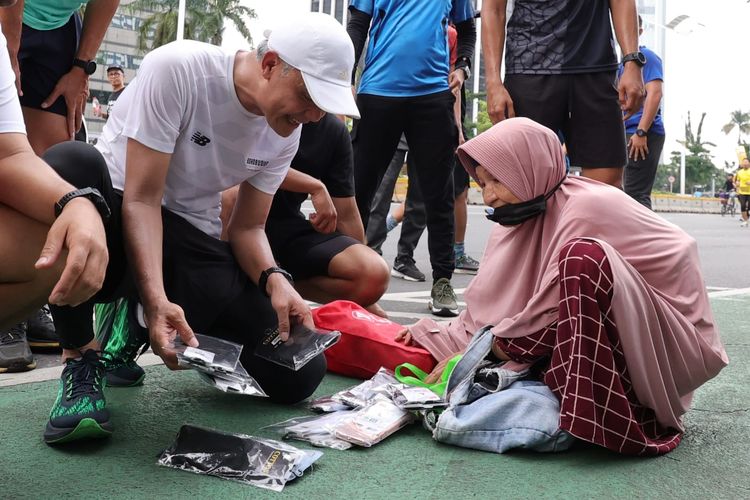 Calon presiden (Capres) nomor urut tiga Ganjar Pranowo memborong kaos kaki yang dijajakan pedagang asal Solo, Siti (59) di kawasan Senayan, Jakarta Pusat, Minggu (10/12/2023).