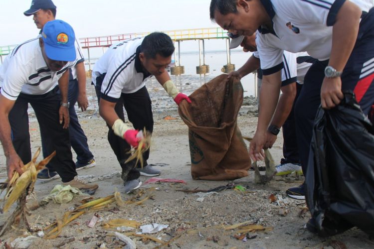 Kapolres Lamongan AKBP Feby DP Hutagalung (tengah) bersama dengan anggota polisi yang lain saat membersihkan sampah di Pantai Kutang, Jumat (22/2/2019).