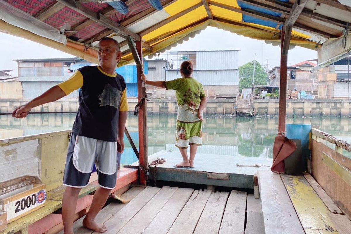 Ajiz (24) tukang ojek perahu di Kali Angke, Jakarta Barat, tengah menarik tali agar perahunya bisa menyeberang, Rabu (2/8/2023). 