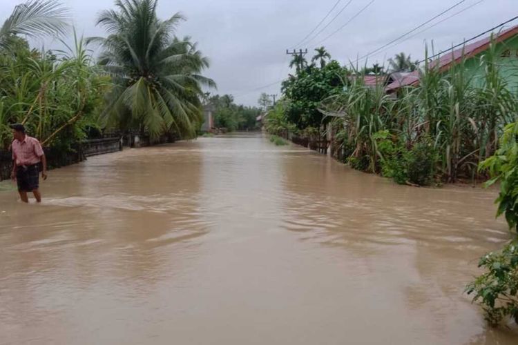 Warga melintas di lokasi banjir di Desa Hagu, Kecamatan Matangkuli, Kabupaten Aceh Utara, Minggu (2/1/2022)