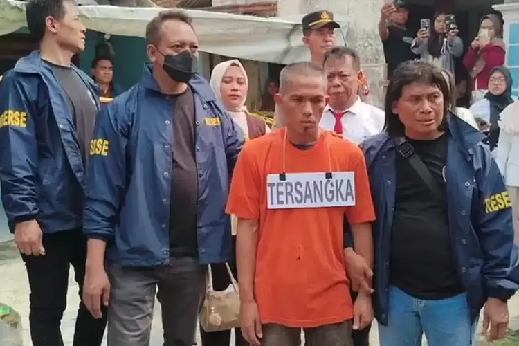 REKONSTRUKSI PEMBUNUHAN SADIS - Tersangka Satuan alias Tuan (42) digelandang menuju mobil petugas usai menjalani rekonstruksi dalam perkara pembunuhan ibu mertua dan KDRT istri, di rumah kontrakan Dusun Sumbertempur, Desa Sumbergirang, Puri, Mojokerto, pada Jumat (22/5/2026). 
