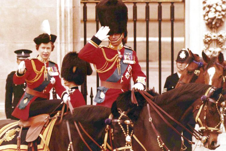 Dalam foto tertanggal 14 Juni 1975, Ratu Inggris Elizabeth II dan suaminya Pangeran Philip memberi hormat dengan menunggang kuda di luar gerbang Istana Buckingham di London, setelah upacara tahunan Trooping of the Color. 