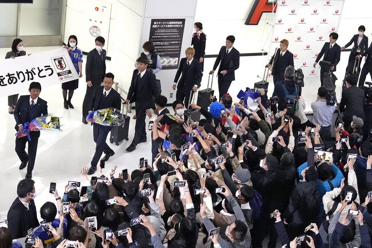 Para suporter menyambut kedatangan tim nasional Jepang termasuk pelatih Hajime Moriyasu (kiri) yang pulang dari Piala Dunia 2022 Qatar, di Bandara Internasional Narita, Rabu (7/12/2022).