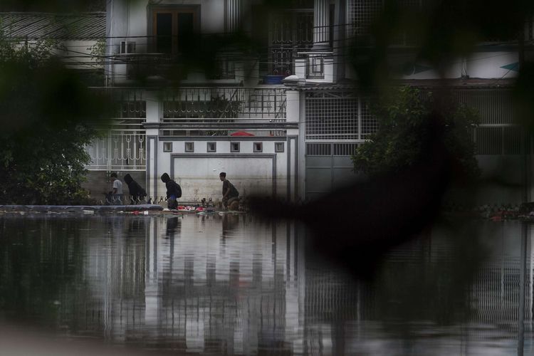 Warga melintasi area waduk yang terendam banjir di wilayah Teluk Gong, Penjaringan, Jakarta Utara, Sabtu (4/1/2020).Hujan lebat di awal tahun membuat kawasan teluk gong masih terendam banjir.