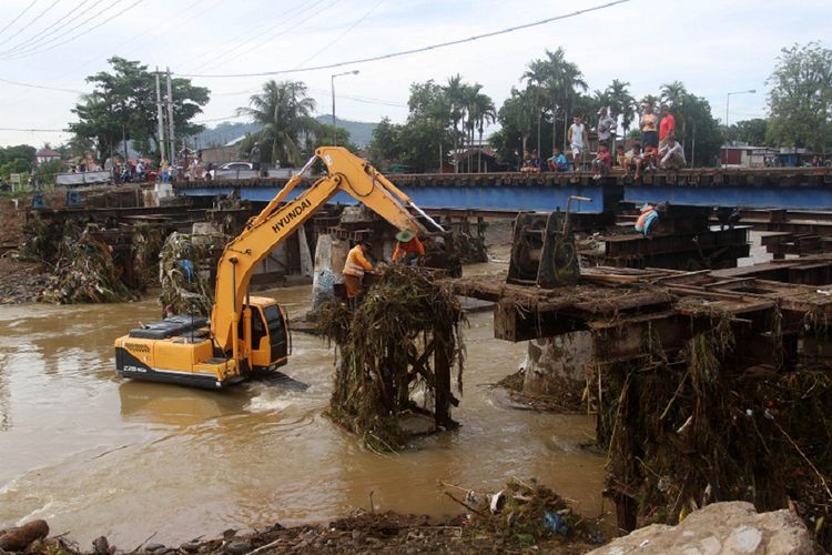 Alat berat membersihkan material banjir berupa kayu dan sampah yang tersangkut di jembatan rel kereta api pasca banjir,  di kelurahan Alai Parak Kopi, Padang, Sumatera Barat, Sabtu (3/11/2018). Banjir yang melanda Kota Padang dan meluapnya debit air sungai mengakibatkan belasan rumah rusak dan dua jembatan putus.  ANTARA FOTO/Muhammad Arif Pribadi/hp.