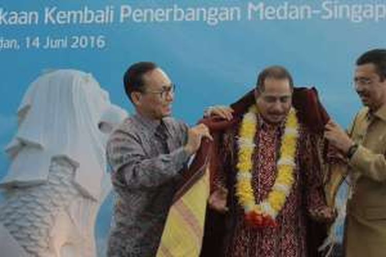 Pemakaian ulos oleh Dirut PT Garuda Indonesia dan Gubernur Sumatera Utara kepada Menteri Pariwisata Arief Yahya sebagai tanda selamat datang atas pembukaan penerbangan perdana Garuda Indonesia rute Singapura-Medan di Bandara Kualanamu, Selasa (14/6/2016).