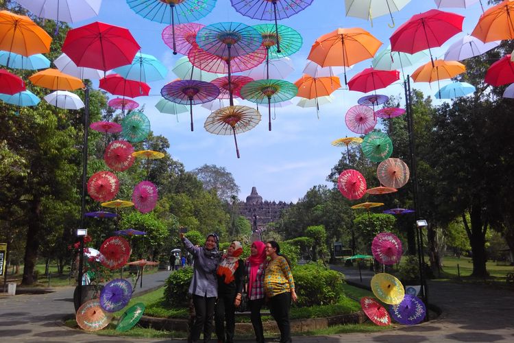 Sejumlah wisatawan asyik berfoto di bawah payung warna warni dengan latar belakang candi Borobudur. Payung ini disediakan selama masa libur Lebaran, 22 Juni - 2 Juli 2017.