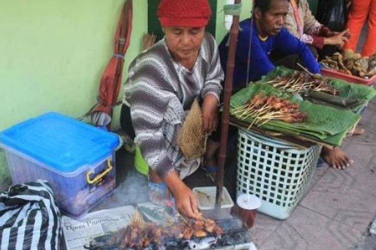 Ponijah membakar sate dagangannya.