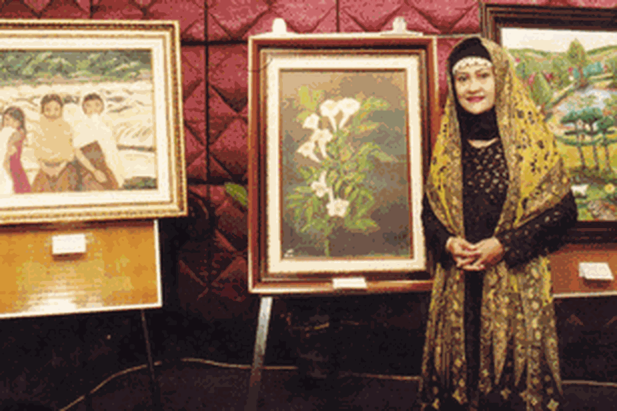 Hj Titi Isnani Djoko berpose di depan karya lukisnya.