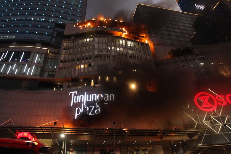 Kobaran api muncul dari Tunjungan Plaza 5 yang terbakar di Surabaya, Jawa Timur, Rabu (13/4/2022). Sejumlah kendaraan pemadam kebakaran dikerahkan termasuk tiga Bronto Skylift untuk memadamkan api yang membakar lantai 5 Tunjungan Plaza 5 itu.